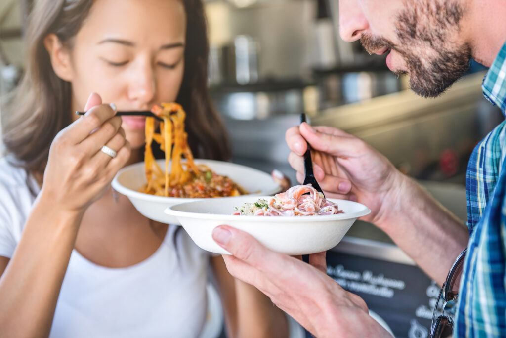 Couple eating pasta from food truck.